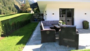 A modern outdoor seating area with a sofa and chairs, a small table, and a potted plant. - Haus Goldmann by Interhome (Ginzling)