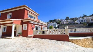 Un bâtiment rouge avec une terrasse en pierre et une balustrade blanche.