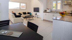 Un salon moderne avec un canapé, un téléviseur et un coin repas.