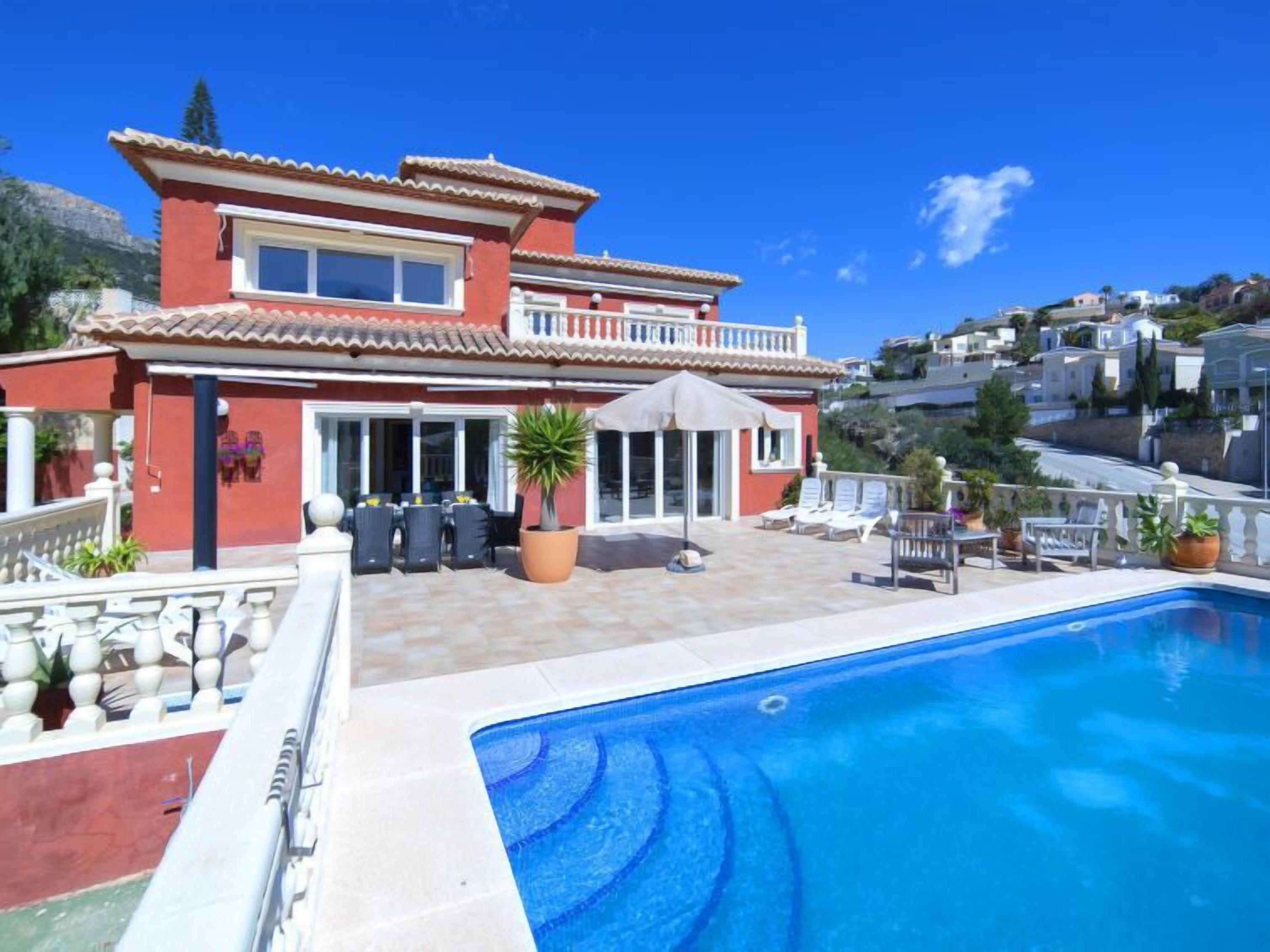 A two-story house with a swimming pool, outdoor seating, and a view of the surrounding neighborhood.