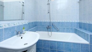Une salle de bain avec un lavabo blanc, une baignoire et des murs recouverts de carreaux bleus.