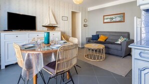 A modern living room with a dining area, a sofa, a television, and a sailboat decoration. - Montaigu by Interhome (Cabourg)