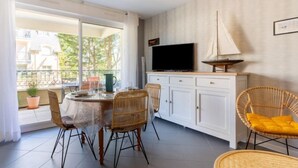 A dining area with a table, chairs, a television, and a sailboat decoration. - Montaigu by Interhome (Cabourg)