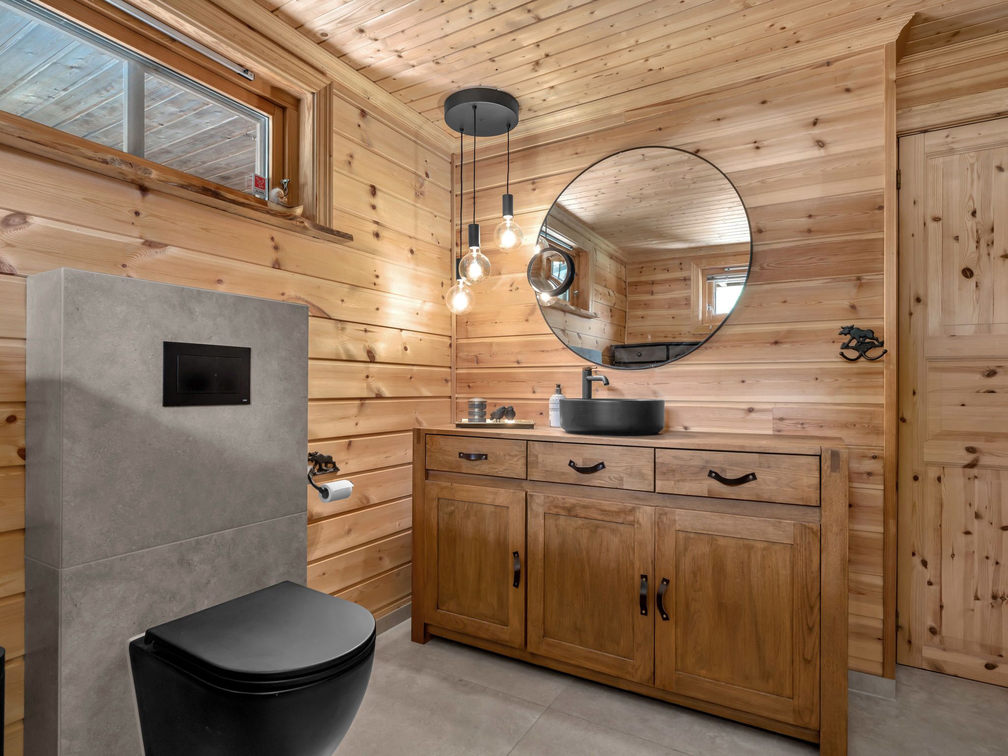 Un baño con paneles de madera, un lavamanos moderno, un inodoro y un espejo.