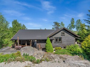 Situated in a serene forest, this cabin features a chimney, a spacious porch, and a wooden deck.