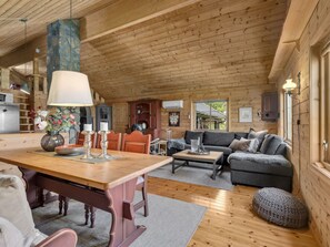 Cozy cabin interior with a dining area and living space, featuring a wooden dining table, sofa, and coffee table.