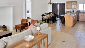 Una sala de estar moderna con sofá, mesa de centro y comedor con sillas.