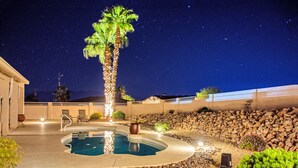 Una piscina con una palmera, rodeada por un muro de piedra y un edificio.