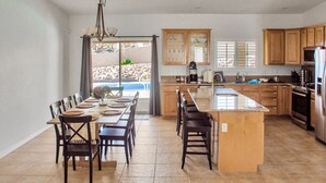 Una cocina amplia con una isla grande, armarios de madera y vistas a una piscina a través de puertas corredizas de vidrio.