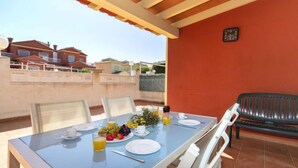 A dining area with a table set for two, a barbecue grill, and a view of houses in the background. - Vacation home Ni Hao by Interhome (Calpe/Calp)