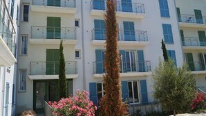A multi-story residential building with balconies, a central entrance, and surrounding greenery. - T2 vue baie by Interhome (Macinaggio)