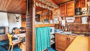 A cozy cabin-style kitchen with wooden walls, a dining area with a table and chairs, and a fireplace. - Vacation home Vesec by Interhome (Liberec)