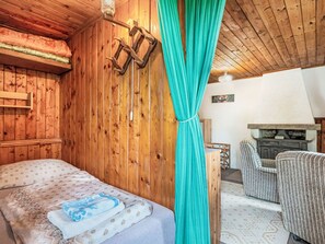 Quarto de cabana de madeira com cama, poltrona e lareira.