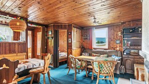 A cozy cabin interior with a dining area, a sofa, and a bookshelf. - Vacation home Vesec by Interhome (Liberec)