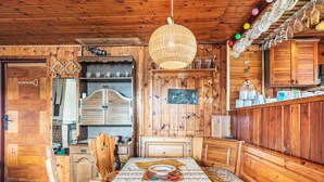 A wooden interior with a dining table set for four, surrounded by wooden cabinets and shelves. - Vacation home Vesec by Interhome (Liberec)