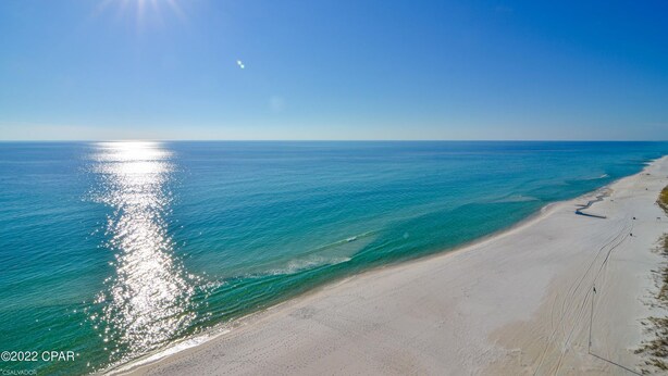 A beach with clear turquoise waters and a sandy shore under a bright sun.