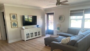 A living room with a grey sofa, a white entertainment unit, and a ceiling fan.