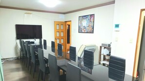 A conference room with a long table, multiple chairs, a projector screen, and a door. - Vacation Rental Maihama (Urayasu)