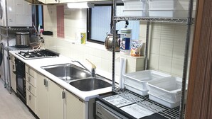 A kitchen with white cabinets, a stainless steel sink, a stove, and a refrigerator. - Vacation Rental Maihama (Urayasu)
