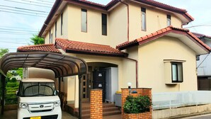 A two-story house with a covered carport, a brick entrance, and a small garden area. - Vacation Rental Maihama (Urayasu)