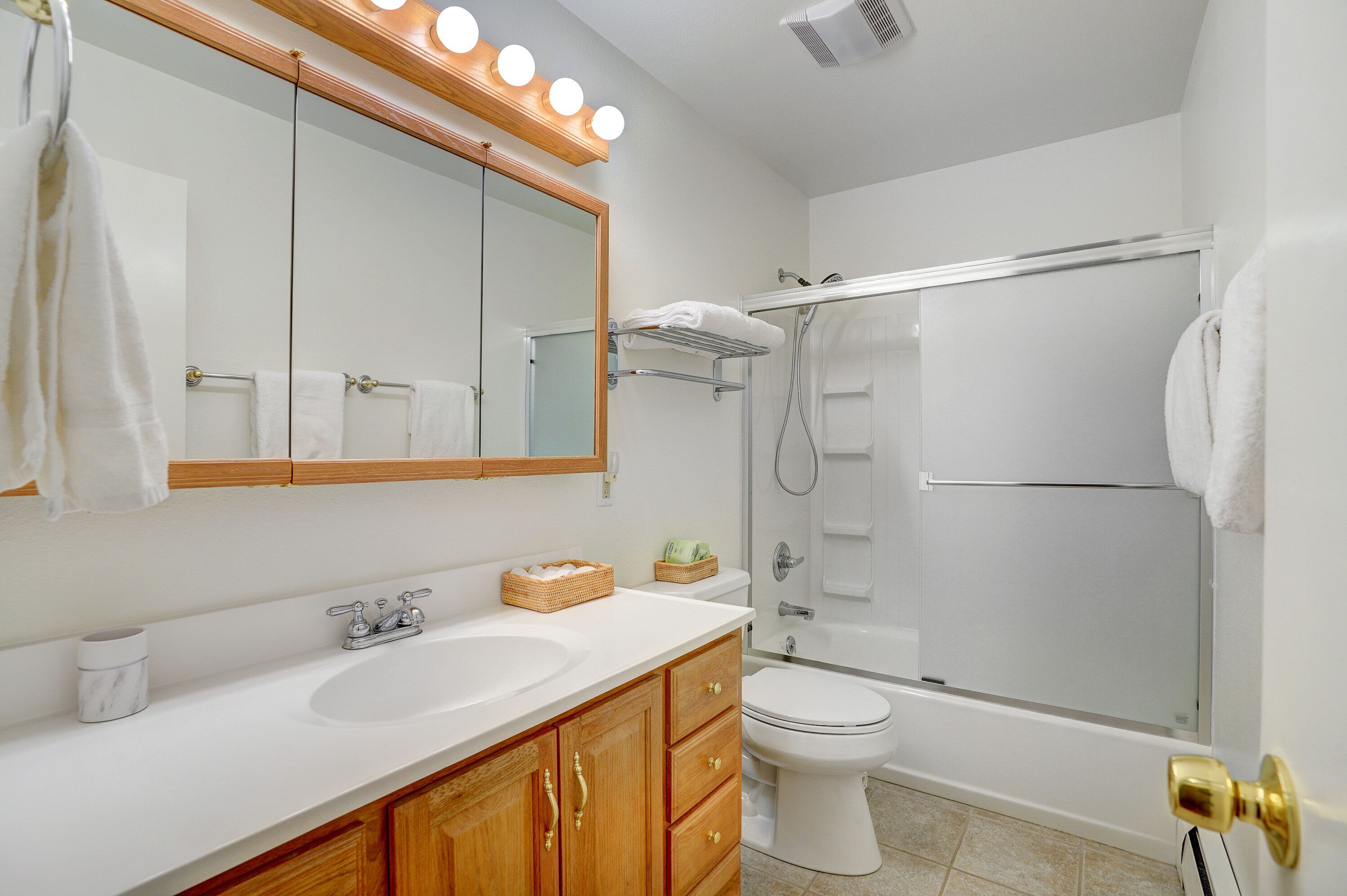 A bathroom with a sink, mirror, and shower.