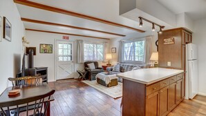 A spacious living area with a fireplace, a dining table, and a kitchen with wooden cabinets. - Rocky Mountain Riverside Escape; 1 Mile to Park (Estes Park)