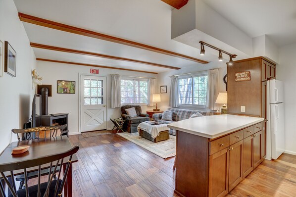A spacious living area with a fireplace, a dining table, and a kitchen with wooden cabinets.