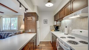 A compact kitchen with wooden cabinets, a white countertop, and a built-in stove. - Rocky Mountain Riverside Escape; 1 Mile to Park (Estes Park)
