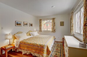 A bedroom with a bed, bedside table, lamp, and a window with curtains.