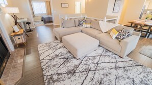 A modern living room with a sectional sofa, a dining table, and a fireplace. - Relaxing home w/king suite in South Anchorage! (Anchorage)