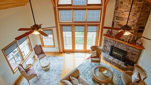 Un salón espacioso con chimenea, ventanas amplias y ventiladores de techo.
