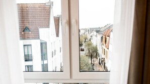 A room with a round table and a view of a street through a window. - Wiechmanns Weserhotel (Brake)