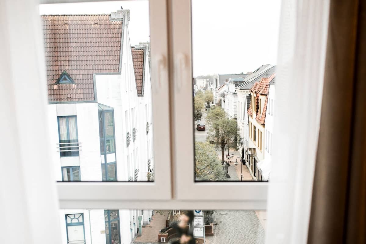 A room with a round table and a view of a street through a window.