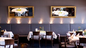 A restaurant with booths and tables, some with white tablecloths. There are framed pictures on the wall. - Wiechmanns Weserhotel (Brake)