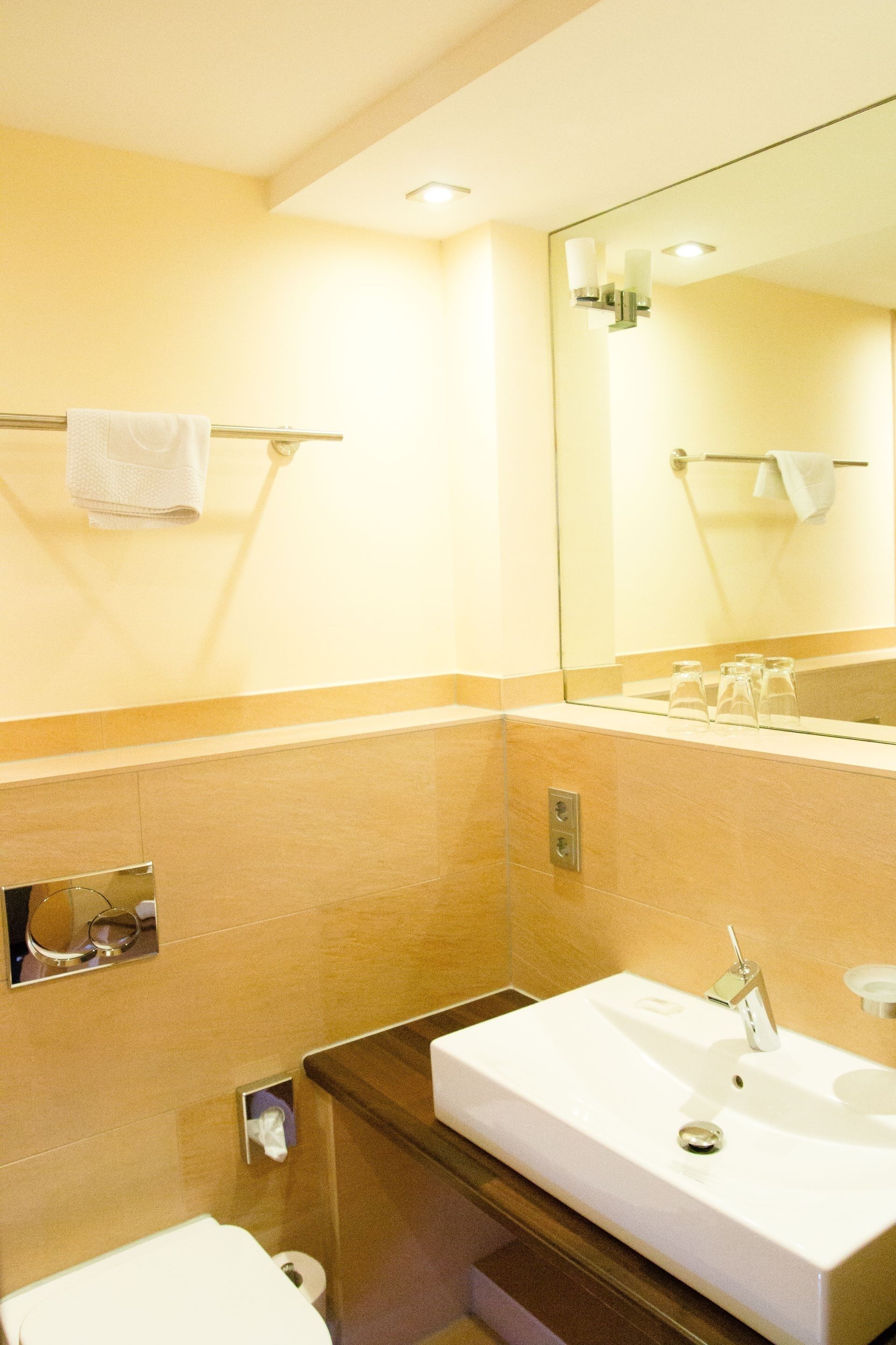 Ein Badezimmer mit einem weißen Waschbecken, einem Spiegel, einem Handtuchhalter und einer Toilette.