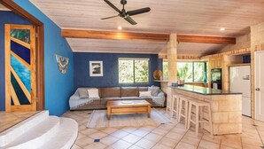 Un espacio habitable amplio con sofá, mesa de centro y una zona de cocina con barra.