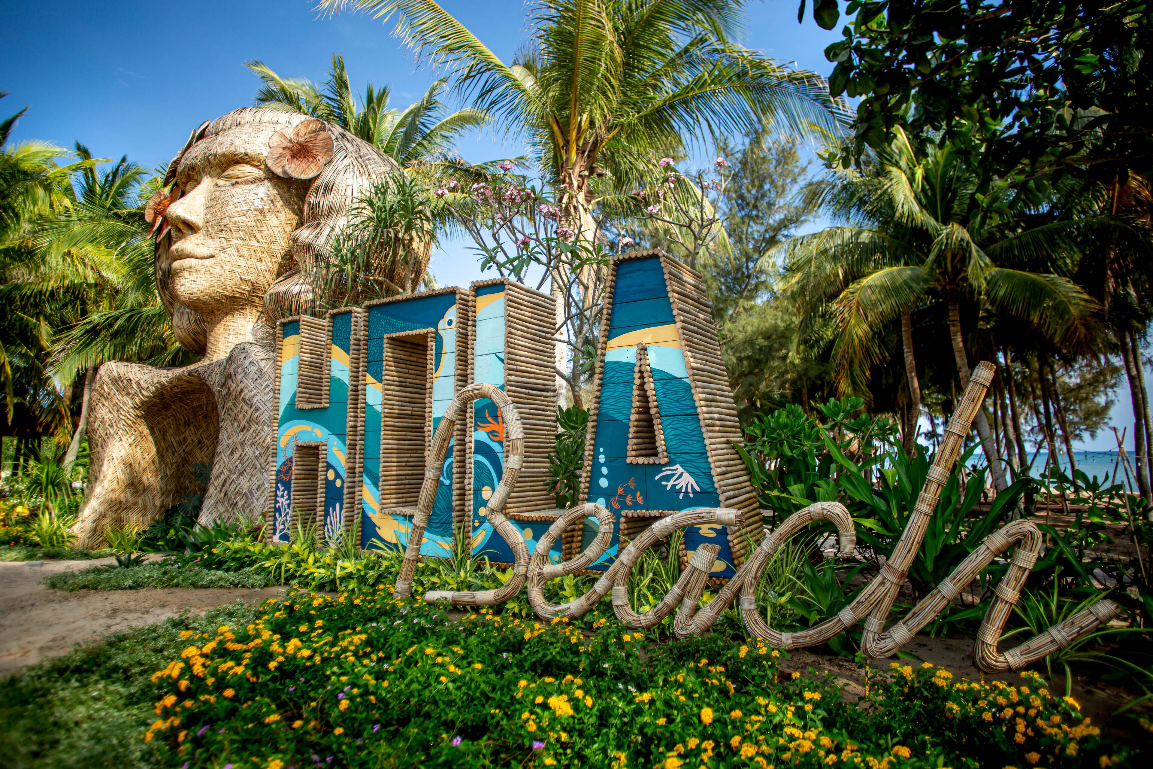 Una escultura grande y colorida con la palabra "Beaches" y una palmera de fondo.
