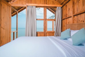 A wooden cabin room with a bed, curtains, and a view of the sea. - Hola Beach-Beach Club & Eco Glamping Resort (Tan Thanh)