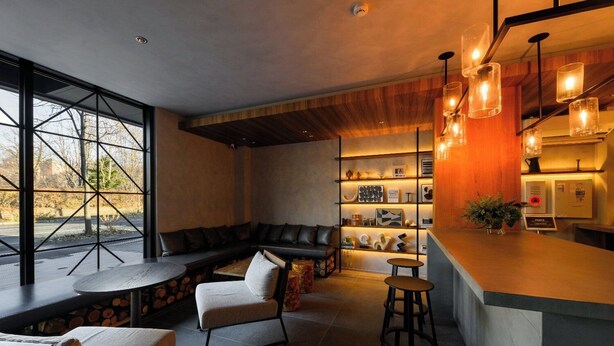 A modern interior with a large window, a wooden ceiling, a bar area, and a seating arrangement. - BROOKLYN HOTEL (Sapporo)