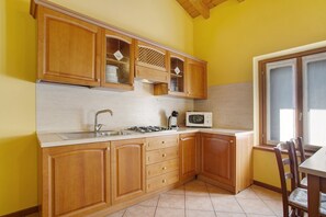 Una cocina con armarios de madera, un lavamanos, una estufa y un microondas.
