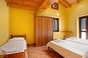 A room with two beds, wooden wardrobe, and a window.