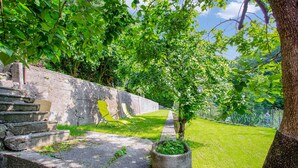 A stone staircase leading to a grassy area with a chair and a potted plant. - 'Residence Appartamento Roma' with Mountain View, Terrace & Wi-Fi (Civate)