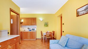 A compact living space with a kitchenette, dining area, and a sofa. - 'Residence Appartamento Roma' with Mountain View, Terrace & Wi-Fi (Civate)