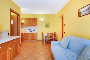 A compact living space with a kitchenette, dining area, and a sofa.