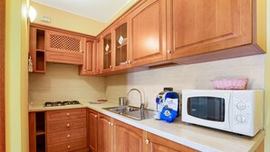 A compact kitchen with wooden cabinets, a gas stove, a sink, and a microwave. - 'Residence Appartamento Roma' with Mountain View, Terrace & Wi-Fi (Civate)