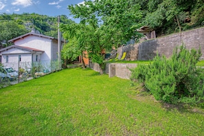 A residential area with a white house, a stone wall, and a grassy yard.