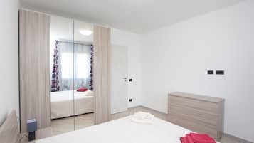 A bedroom with a bed, a dresser, a mirror, and a window with curtains.