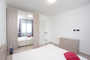 A bedroom with a bed, a dresser, a mirror, and a window with curtains.