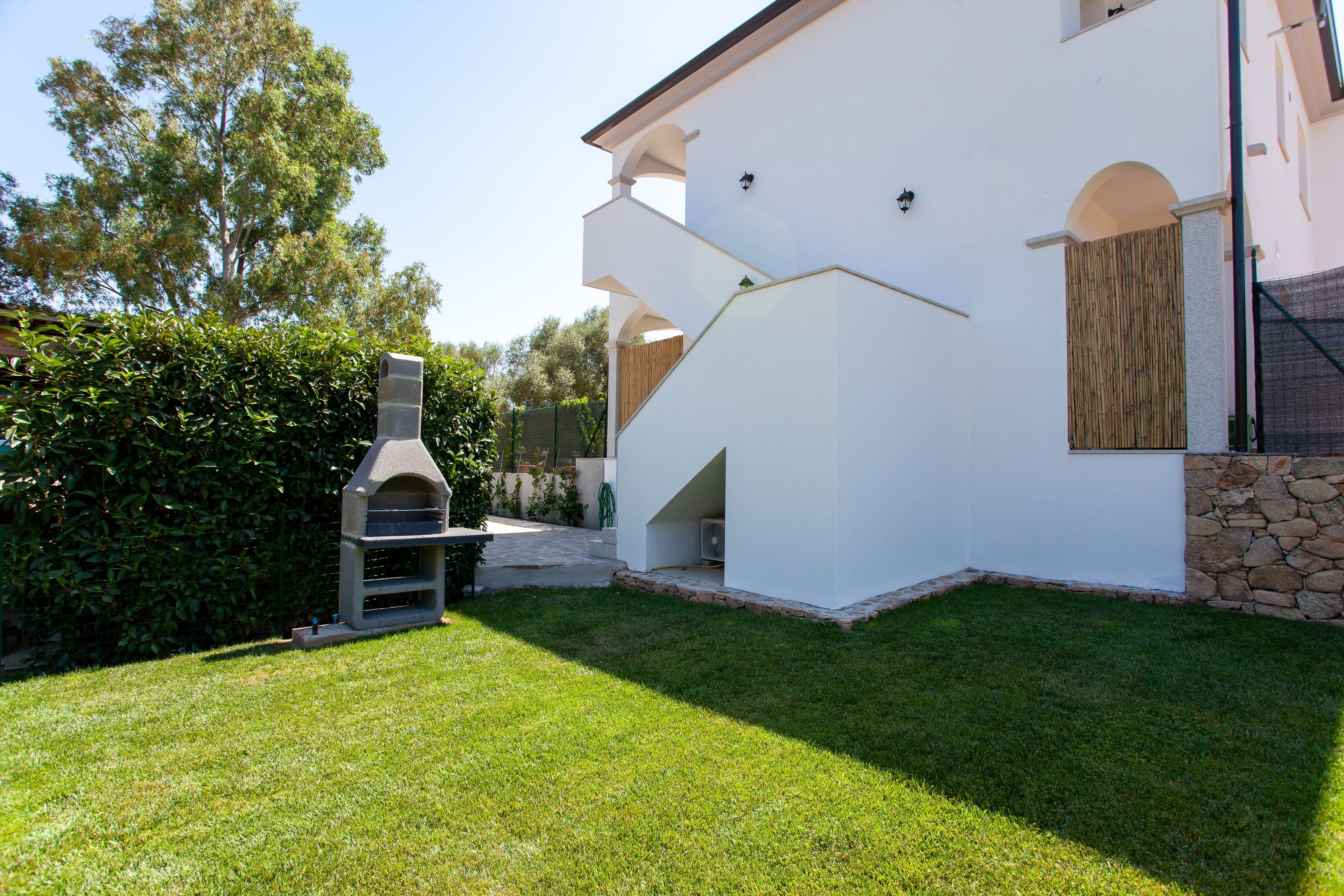 A modern house with a stone foundation, a white exterior, and a well-maintained lawn.