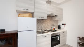 Een moderne keuken met een witte koelkast, een gasfornuis en een inbouwoven.